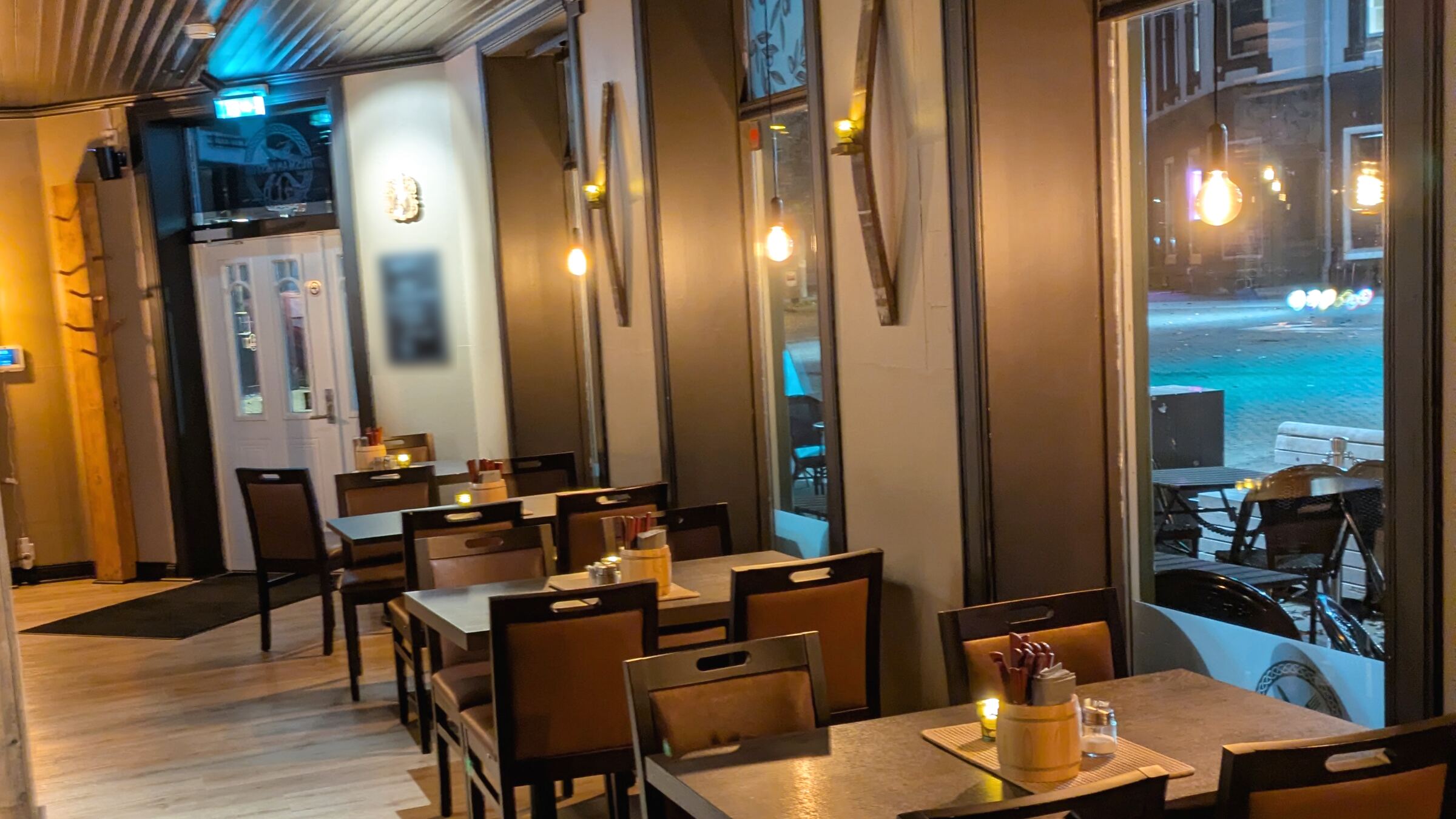 Restauranten i 1. etasje, med bord langs vinduene mot gata og pendellamper i vinduene